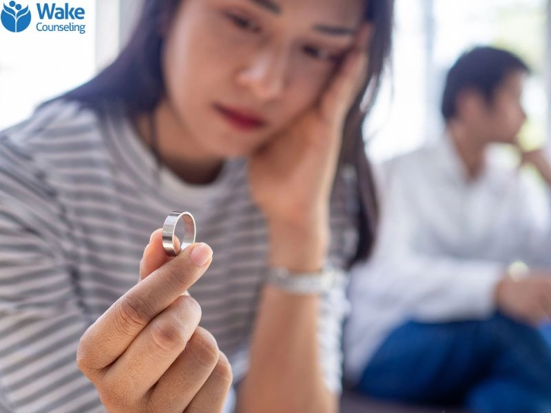 A woman holding a ring appears to be in distress from an extramarital affair.