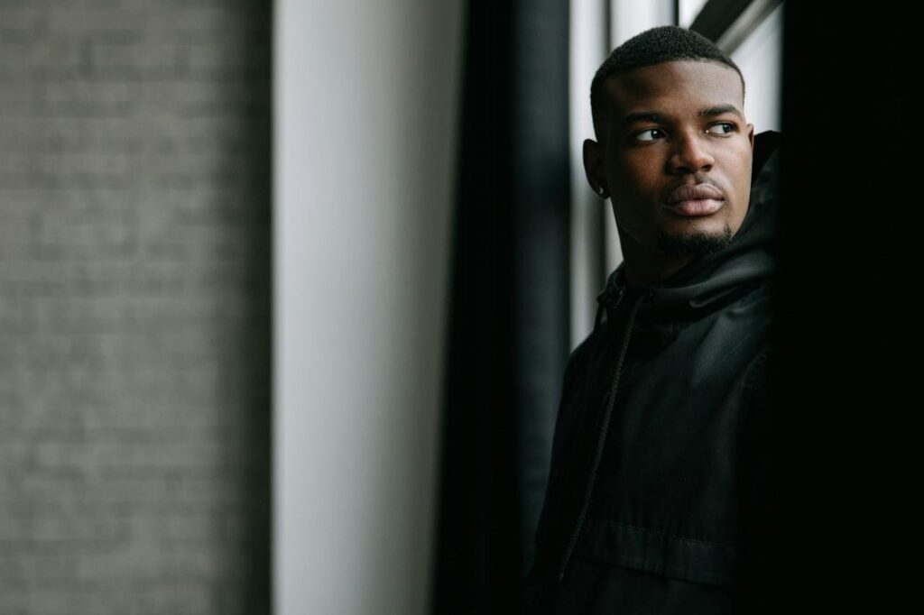 man-in-black-jacket-standing-near-a-window