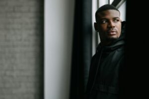man-in-black-jacket-standing-near-a-window