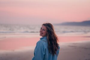 young-woman-walking-on-a-beach-at-sunset